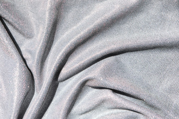 Background of light gray draped fabric with silver lurex thread. Beautiful fashionable fabric with a shiny thread for making clothes. Neutral background texture.