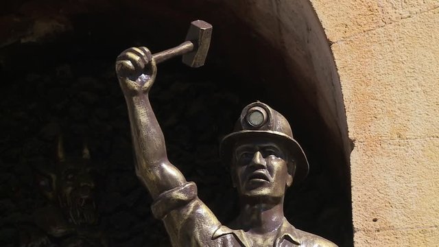 Close-up low-angle still shot of monument of a historical miner standing and raising up his hammer as a show of determination, Oruro, Bolivia