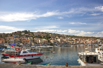 Fototapeta na wymiar Acitrezza Sicily, cyclopean town and tourist harbor with boats, blue sky