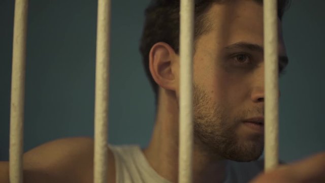 Man behind bars looking around with angry or frustrated face