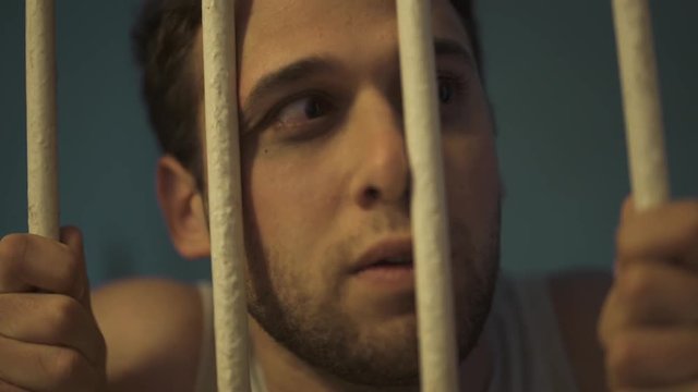 Man shows up behind bar - looking outside his cell