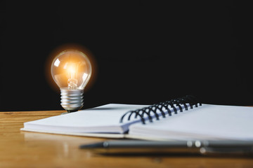 Closeup light bulb on the desk with notebook in office and in financial,accounting,energy,idea...