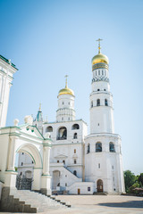 Tilt down on Ivan the Great Bell Tower cathedral inside Moscow Kremlin with clouds and blue sky in background