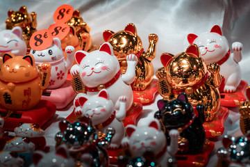 Fortune cats. Oriental souvenirs, mass produced for international export and trade. Close up shot, artificial lighting. Concept image for economic war between China and America. 