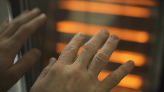 Hands next to a radiator in a cold day
