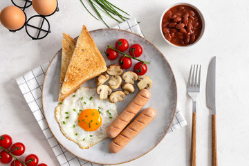 Traditional English Breakfast: sausages, grilled tomatoes and mushrooms, egg, baked beans and bread. Top view