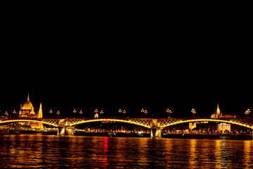 Fototapeta premium night Budapest, glowing in gold. The bridge over the Danube is illuminated by light bulbs. photo from the river