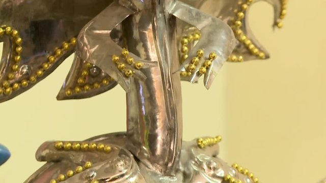 Extreme close-up, low angle tilting shot of a metallic decorated carnival mask of Diablesa at an artisan's workshop, Oruro, Bolivia