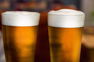 Two glasses of beer on table in restaurant with blurred background