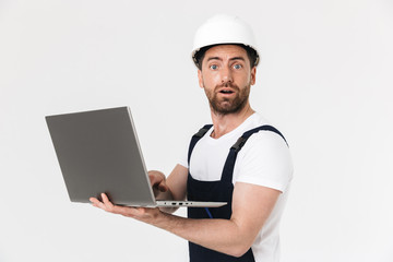 Confident bearded builder man wearing overalls standing