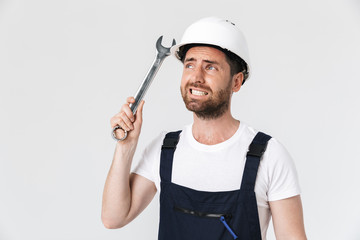 Confident bearded builder man wearing overalls standing