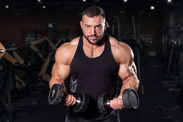 Fototapeta na wymiar biceps. young man lifting weights in gym. barbell. Bodybuilder in the gym. Sports photo shoot. Man's fitness. Training and exercises with dumbbells. Men's photo shoot in low key. Athletic build. weigh