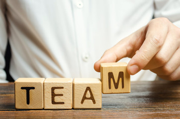 Businessman holds wooden blocks with the word Team. Team management concept. Teamwork. Hiring....
