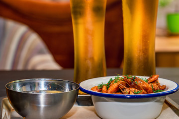 Prepared shrimps with dill in bowl on table with two beer glasses and water