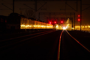 A suburban train standing at night on a siding.