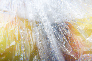 Bolsa de plástico en la cual hay dos manzanas, la bolsa está llena de gotas de agua