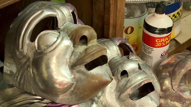 Close-up low-angle tilting shot of stacked finished, unpainted, sheet metal carnival masks at a small local tinsmith workshop in Oruro, Bolivia