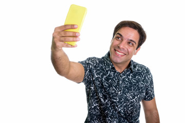 Studio shot of young happy Persian man smiling while taking self