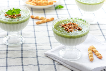 Milk dessert with kiwi. Pana cotta with green kiwi jelly in glass bowls. Sweet breakfast in bright colors.