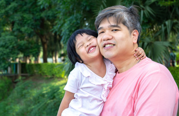 Fototapeta premium An Asian father is carrying a lovely daughter to her chest. Both the father and daughter smiled happily. Asia family and love concept