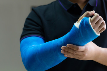 Close up man holding hand with blue bandage as arm injury concept.