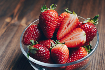 strawberries in a glass bowl on wooden background