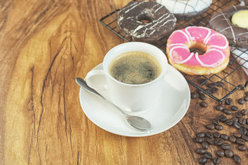 Coffee and donuts on wooden table.