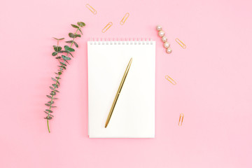 Notebook with gold pen, on pink background. Flat lay. Top view.