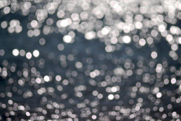 Natural abstract sea water background with bokeh from sun glare on water.
