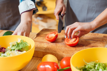 Women making salad. Cutting tomato preparing wholesome vegetarian meal. Mother daughter teaching...