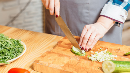 Woman preparing salad. Hands cutting chopping cucumber making wholesome vegetarian meal. Balanced foods dieting.