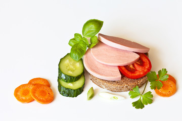 Appetizing sandwich with boiled sausage and vegetables: tomato, cucumber, carrots and basil for breakfast. Place for text, white background, closeup