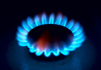 Burning blue gas on the stove. Focus on the front edge of the gas burners