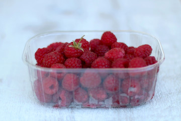 Package full of freshly picked raspberries. Selective focus.