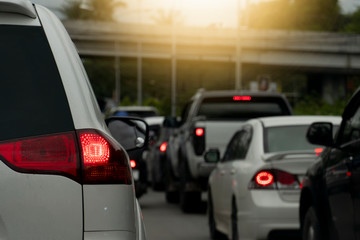 Back side of white car on the road with traffic . Driving  trip to travel in Thailand.  Turn on the brake light.