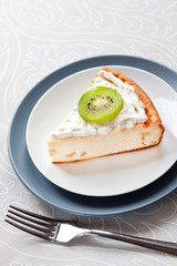 Homemade cottage cheese cake with kiwi fruit and cream on a plate