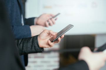 Social media addiction. Modern corporate lifestyle. Business men standing in row, using smartphones. Blur background.