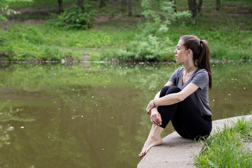 Beautiful woman meditating by the water
