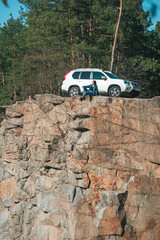 woman sitting on cliff with beautiful view at sunny day. suv car at background