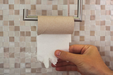 hand with torn toilet paper at the end