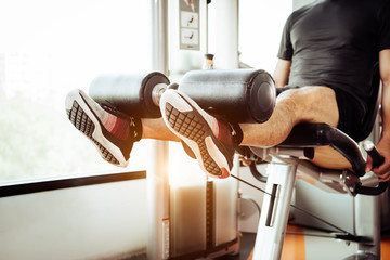 Close up of man lifting weight by two legs for stretching muscle at fitness gym at private...