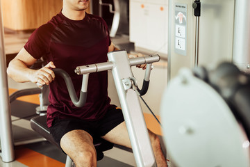 Front view of sport man using back muscle stretch machine called seated row in fitness gym. People lifestyles and Sport workouts concept. Close up view