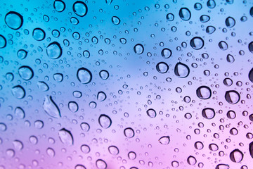 colored raindrops on glass close up