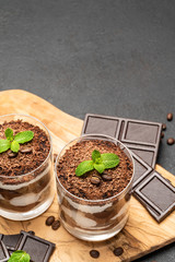 Classic tiramisu dessert in a glass on dark concrete background