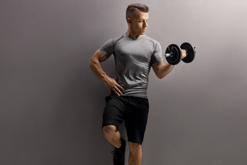 Naklejka premium Young muscular man lifting a dumbbell