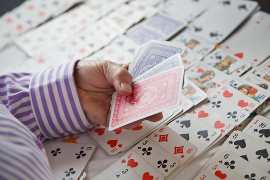 Closeup of wrinkled hands of senior lady playing solitaire