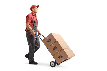 Young male worker in a uniform pushing boxes on a hand truck