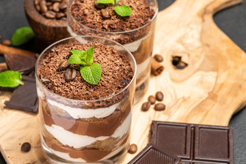 Classic tiramisu dessert in a glass on dark concrete background