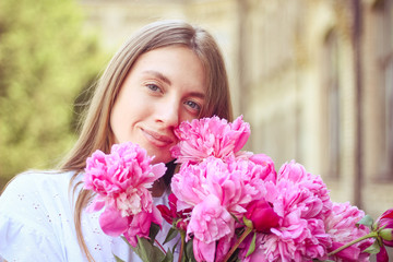 Fototapeta premium beautiful girl, no makeup, natural beauty, feminism. woman in a white dress, crosswise with a bouquet of peonies