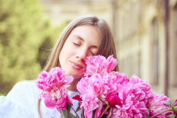 Fototapeta premium beautiful girl, no makeup, natural beauty, feminism. woman in a white dress, crosswise with a bouquet of peonies